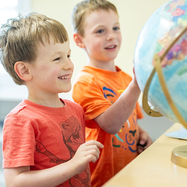 two preschool boys looking at a globe