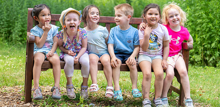 six preschool Rockwell students on an outside bench