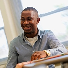 male student smiling while sitting at a desk