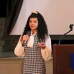 Femaie college student giving a presentation while holding a microphone