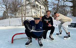 three boys playing outdoor hockey 