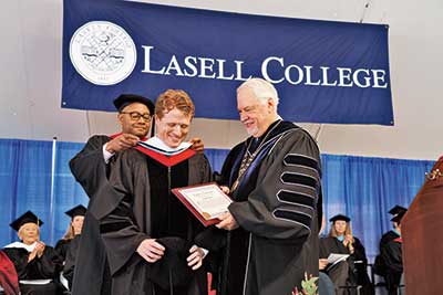 Board of Trustees Chairman Keon Holmes bestows Congressman Joseph Kennedy III with an honorary doctorate of humane letters at the Lasell Commencement ceremony. President Michael B. Alexander looks on. 