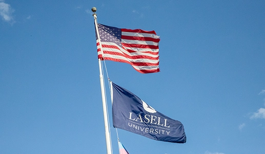 United States flag and Lasell flag on a flagpost