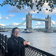female student by river with London Bridge in background